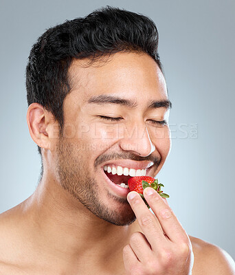 Buy stock photo Man, fruits and beauty studio for wellness, eating strawberry and natural teeth whitening on background. Asian, male model and eyes closed or happy, organic and brightening antioxidants for oral care