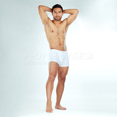 Buy stock photo Shot of a handsome muscular man posing against a studio background