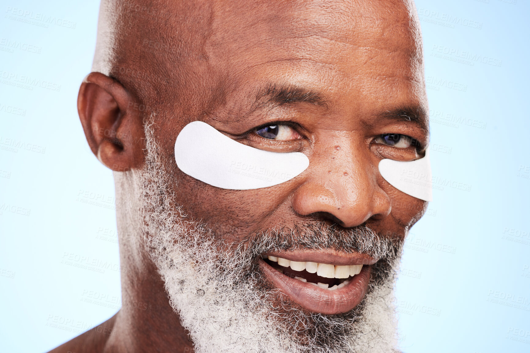 Buy stock photo Black man, portrait and skincare in studio with eye mask for cleaning, smooth and skin moisturizer. Mature person, beauty and dermatology on blue background with patch for wellness or hyaluronic acid