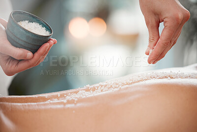 Buy stock photo Shot of a masseuse pouring exfoliating salt scrub onto a clients back