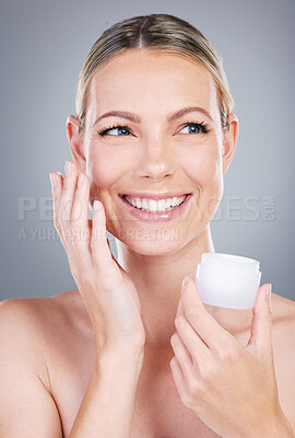 Buy stock photo Happy woman, thinking and lotion with container for skincare or moisturizer on a gray studio background. Young female person or model with smile for facial ointment, cream or anti aging cosmetics