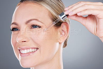 Buy stock photo Studio shot of an attractive mature woman applying serum to her face against a grey background