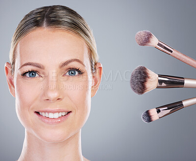 Buy stock photo Studio portrait of an attractive mature woman posing alongside a collection of makeup brushes against a grey background