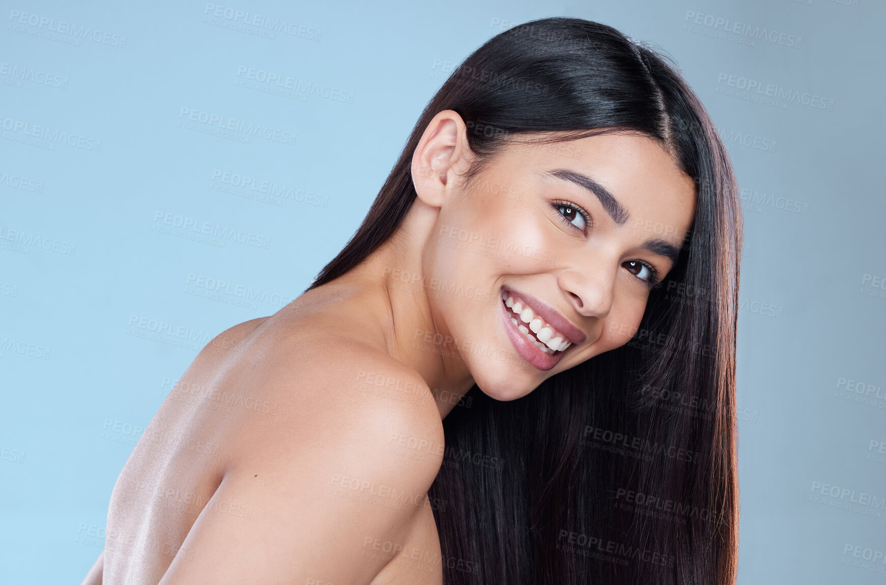 Buy stock photo Studio portrait of a beautiful young woman showing off her long silky hair against a blue background