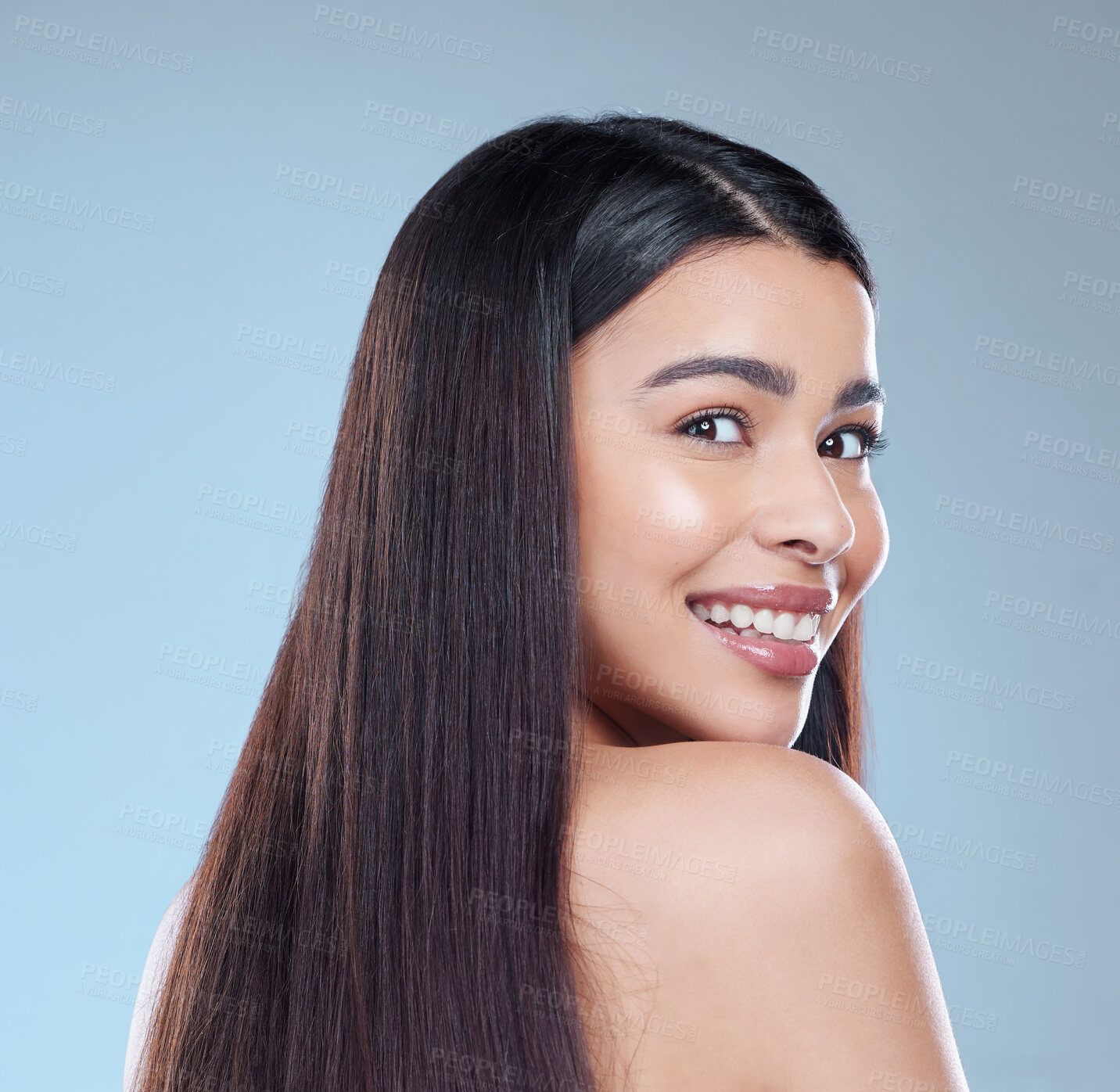 Buy stock photo Studio portrait of a beautiful young woman showing off her long silky hair against a blue background