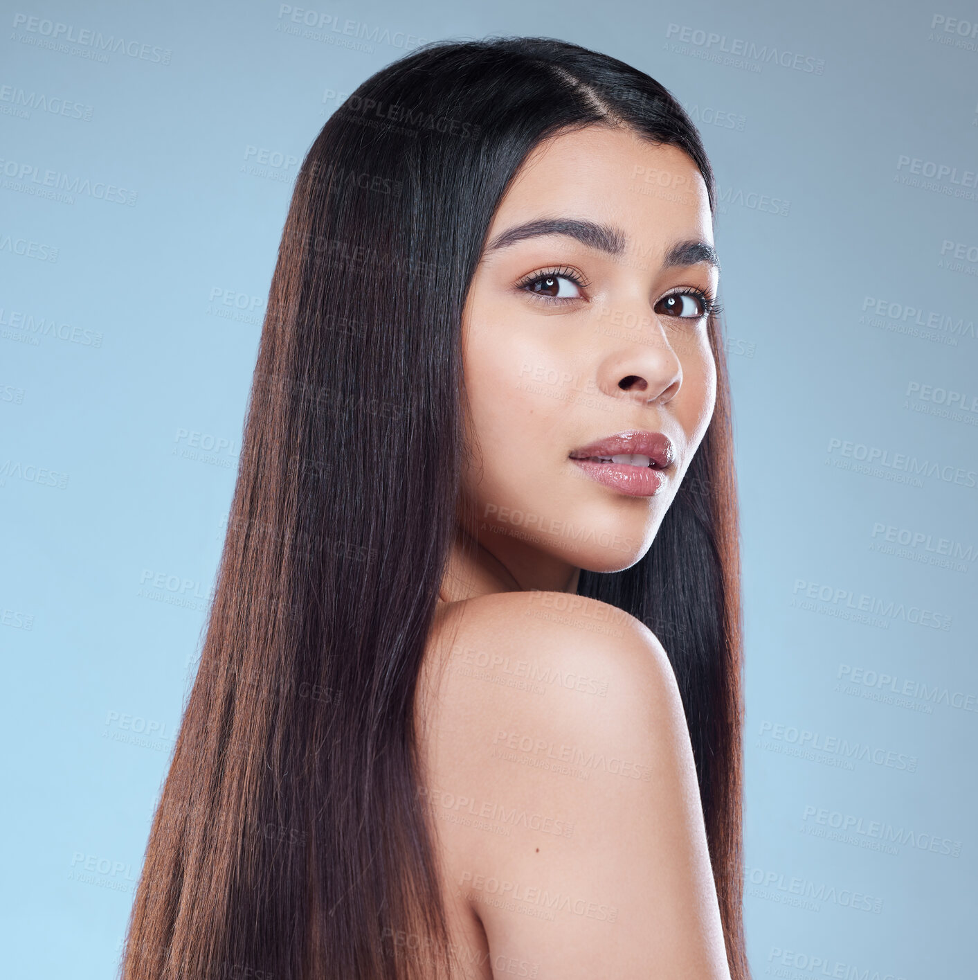 Buy stock photo Studio portrait of a beautiful young woman showing off her long silky hair against a blue background