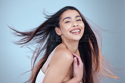 Buy stock photo Studio portrait of a beautiful young woman showing off her long silky hair against a blue background