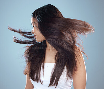 Buy stock photo Studio shot of a beautiful young woman with flowing hair against a blue background
