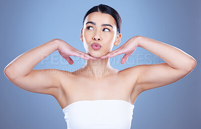 Buy stock photo Shot of an attractive young woman posing alone against a blue background in the studio and feeling playful