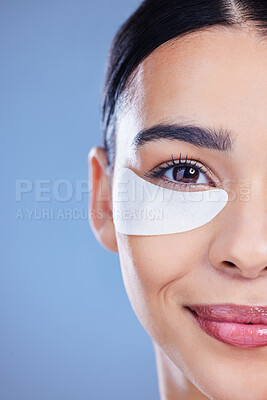 Buy stock photo Cropped shot of an attractive young woman posing alone against a blue background in the studio with an under-eye patch