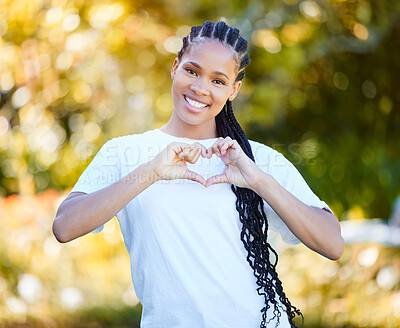 Buy stock photo Closeup shot of a beautiful young woman forming a heart shape while standing outside