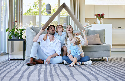 Buy stock photo Full length shot of an affectionate family of four holding a cardboard roof over their heads while sitting in the living room at home