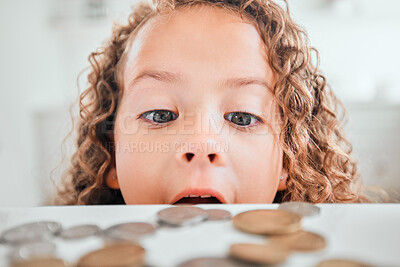 Buy stock photo Shot of a little girl looking surprised while looking at coins on a table at home