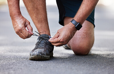 Buy stock photo Hands, shoes and running with a senior man tying his laces outdoor on a road during a cardio workout. Fitness, exercise or footwear with a male runner getting ready for endurance training on a street