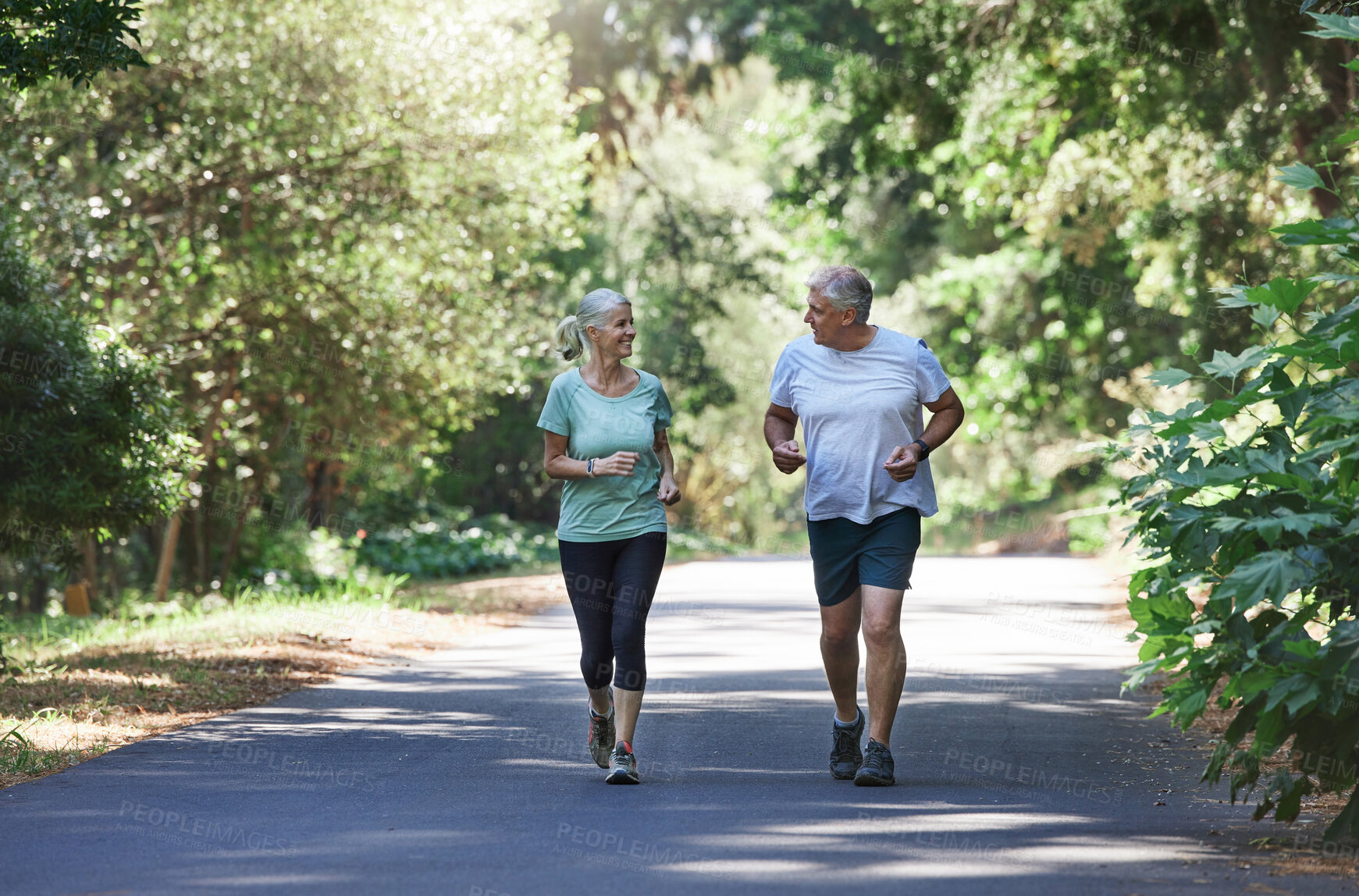 Buy stock photo Senior couple, exercise and happy outdoor for a run, workout and training on road for fitness. Elderly man and woman talking about cardio for health and wellness while jogging or running in nature