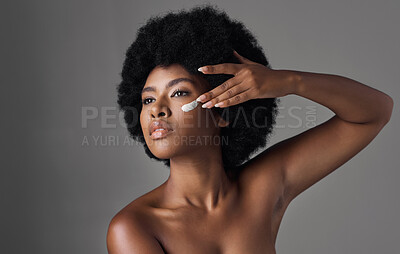 Buy stock photo Beauty, skincare and black woman with cream on face, afro and cosmetics in studio on grey background. Natural skin care product, lotion and African model with salon glow and dermatology for wellness.