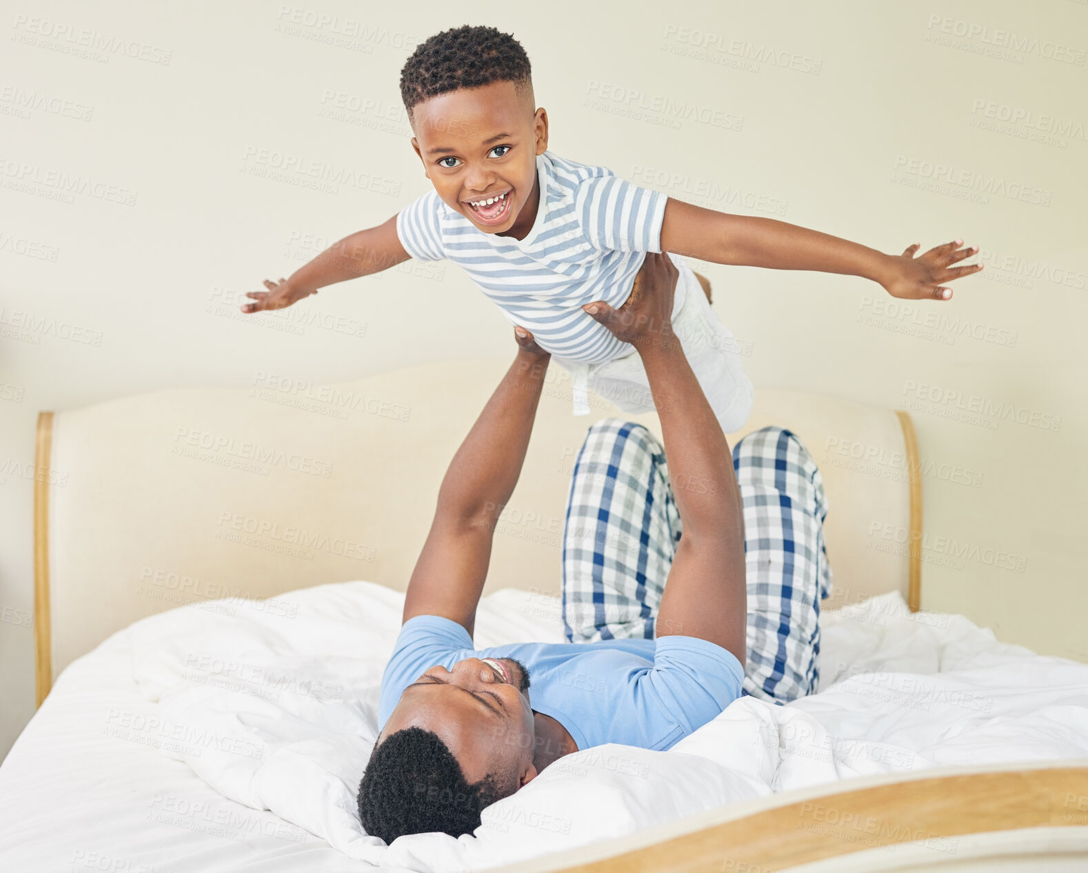 Buy stock photo Shot of a young father lying down and bonding with his son while playing with him at home