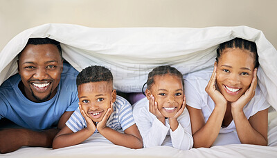 Buy stock photo Shot of a young family bonding together while lying on the bed at home and under the duvet