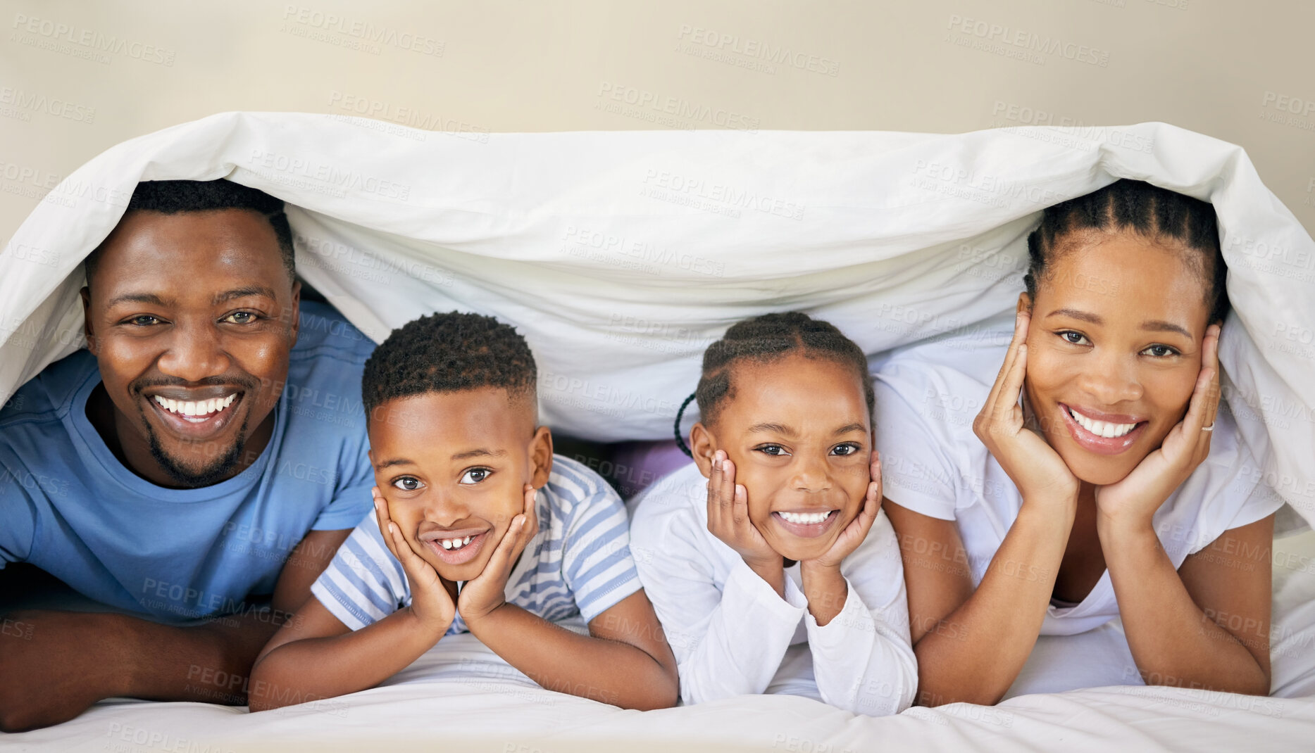 Buy stock photo Shot of a young family bonding together while lying on the bed at home and under the duvet