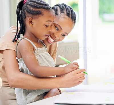Buy stock photo Shot of an attractive young woman sitting and bonding with her daughter while helping her colour