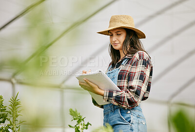 Buy stock photo Shot of a young female farmer taking note of her produce progress