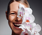 Beautiful mature woman posing with flowers in studio against a grey background
