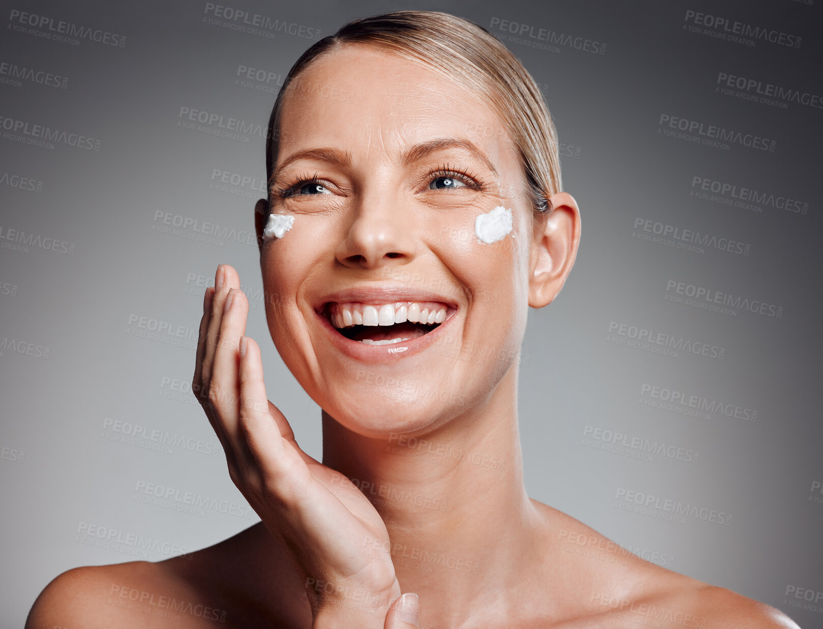Buy stock photo Beautiful mature woman posing with face lotion in studio against a grey background