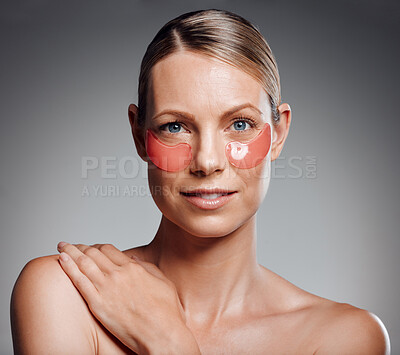 Beautiful mature woman posing with under eye patch in studio against a grey background