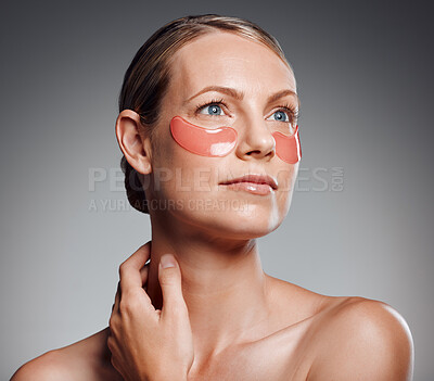 Beautiful mature woman posing with under eye patch in studio against a grey background