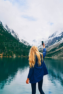 Buy stock photo Water, photography and back of person, smartphone and tourist on hike, lake or picture of adventure. Travel, influencer and mobile for memory, river and view of mountain, holiday or scenery of Canada