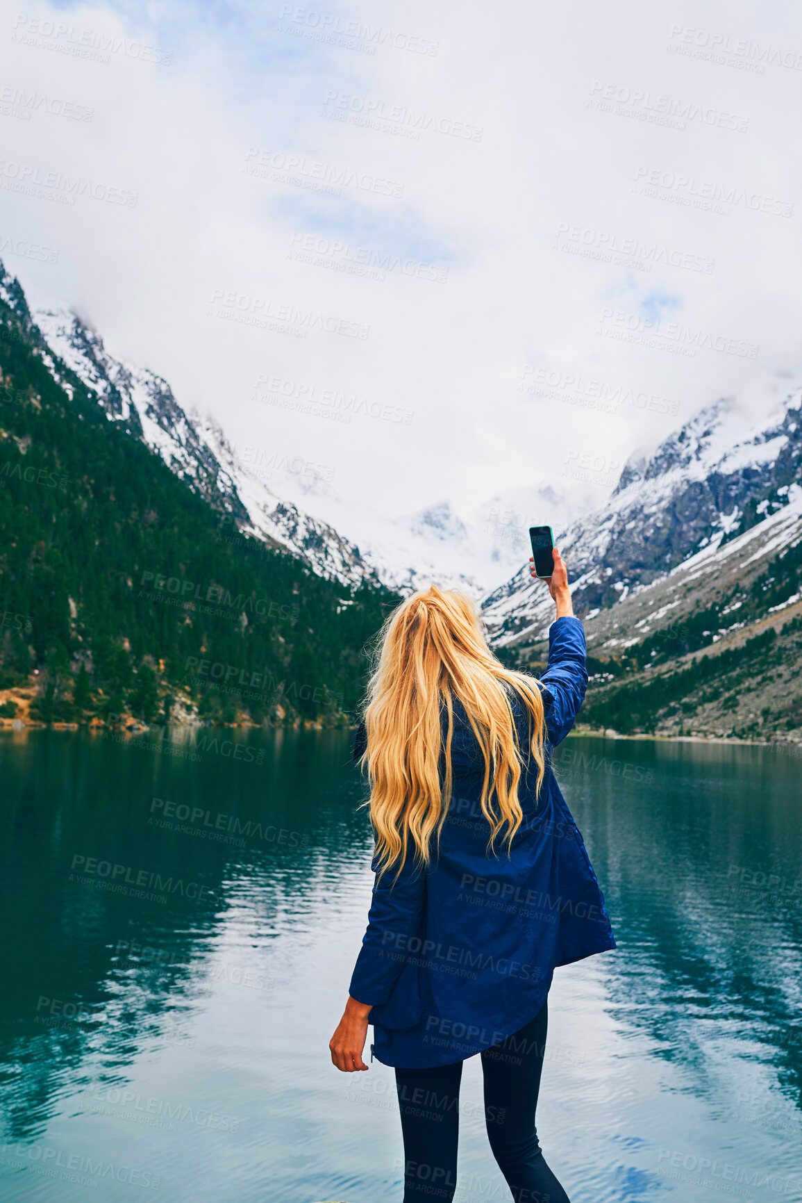 Buy stock photo Water, photography and back of person, smartphone and tourist on hike, lake or picture of adventure. Travel, influencer and mobile for memory, river and view of mountain, holiday or scenery of Canada