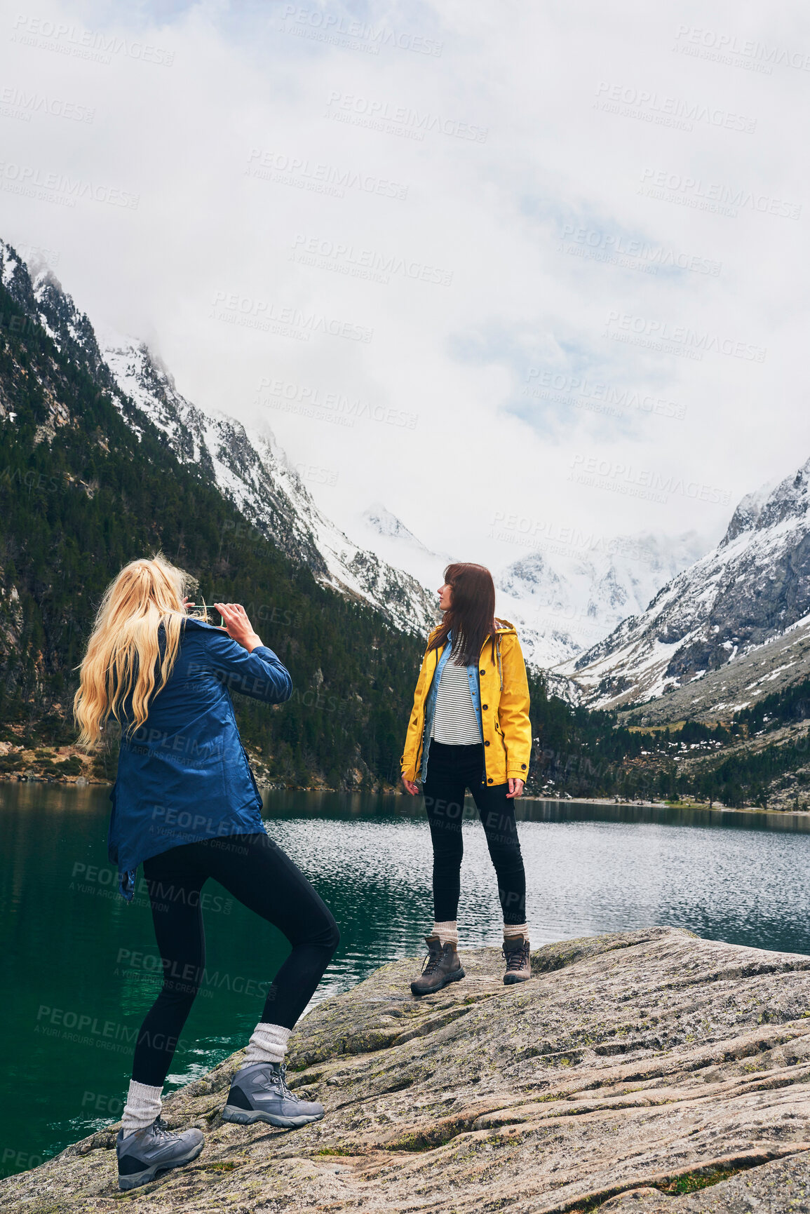 Buy stock photo Mountain, photography and friends with smartphone, lake and women on hike, outdoor and picture of adventure. Travel, influencer and mobile for memory, river and view of water, holiday and Canada