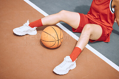Closeup of a sporty woman sitting on a basketball court. Taking a break after playing a match
