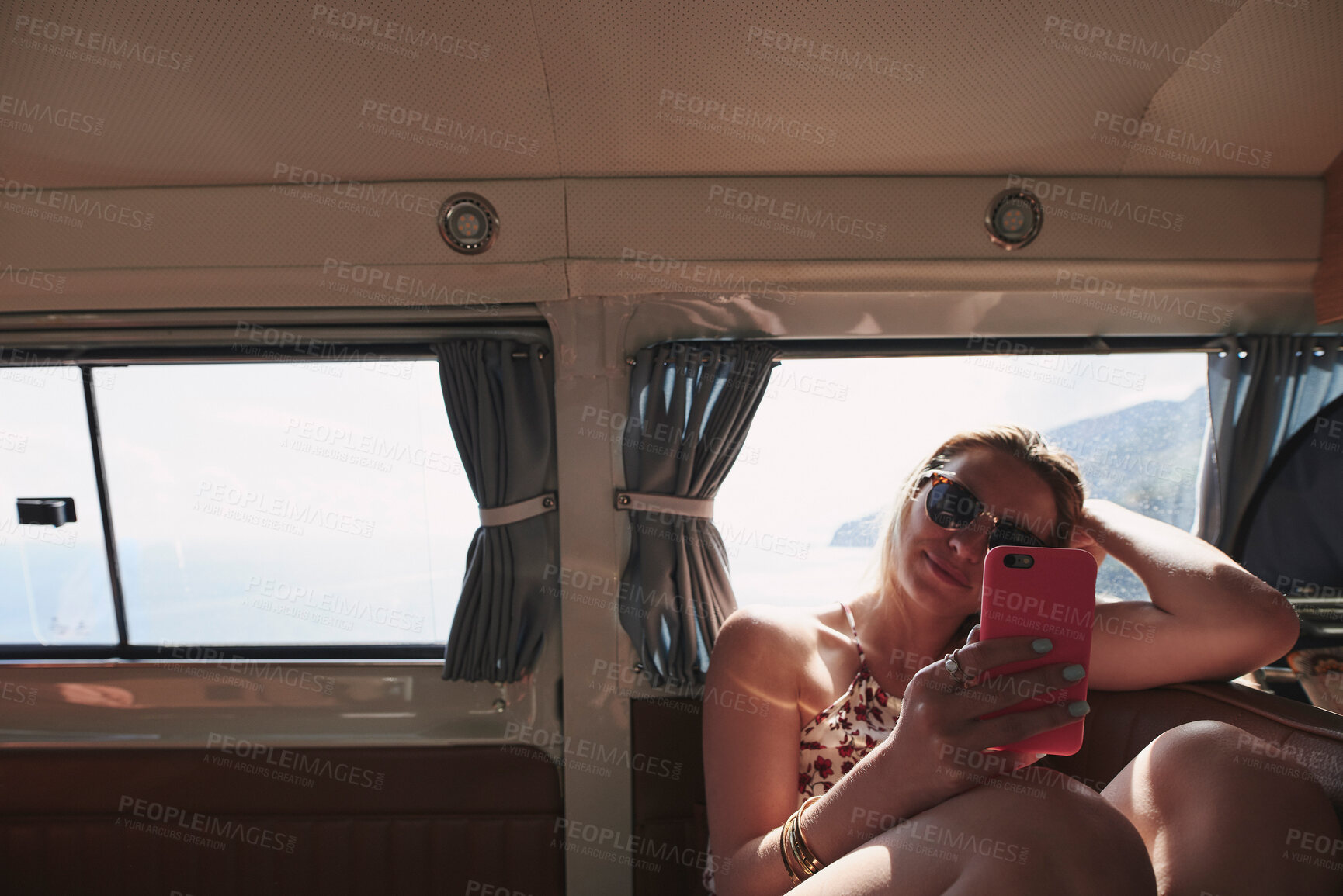 Buy stock photo Shot of an attractive young woman sitting in a car and using her cellphone during her holiday in Italy