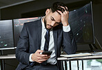 Stressed businessman using a smartphone, trading on the stock market in a financial crisis. Trader working online in a bear market with stocks crashing. Market crash and economy depression or failure