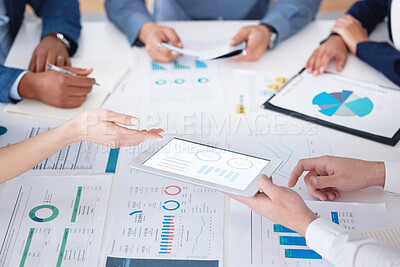 Unknown group of diverse businesspeople using a digital tablet during a boardroom meeting in an office. Closeup of colleagues planning and using paperwork and technology to brainstorm for strategy