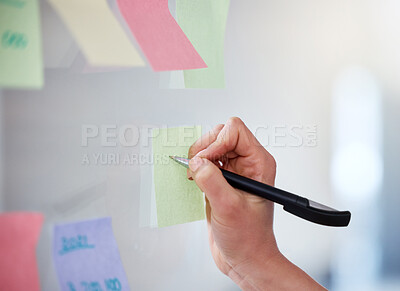 Buy stock photo Closeup of unknown business woman writing on sticky notes on a transparent board to brainstorm in an office. Caucasian professional sticking a note on visual aid while planning a strategy with ideas