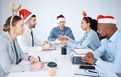 Buy stock photo Diverse group of business people wearing Christmas hats while talking in meeting over festive season. Team of professional colleagues sitting together, brainstorming and planning a strategy in office