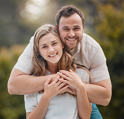 Portrait of loving young caucasian couple spending time together outdoors on a sunny day. Handsome smiling man holding and embracing his beautiful wife while bonding at the park.