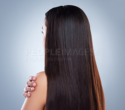 Close up of a young woman with beautiful long smooth hair. Young mixed race woman with luxurious straight and shiny brown hair. Healthy hair against studio background