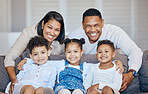 Portrait of young smiling mixed race family embracing each other and bonding in the living room at home on a weekend. Hispanic mother and father touching their children. Loving parents and siblings