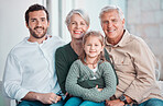 Cute little girl sitting on the couch together with family. Happy child sitting with her father and grandparents at home. Caucasian family smiling while relaxing together during a visit