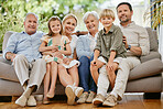Portrait of a smiling multi generation caucasian family sitting close together on the sofa at home. Happy adorable children bonding with their mother, father, grandfather and grandmother on a weekend