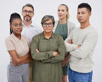 Buy stock photo Portrait of a group of multiracial business team standing together with arms crossed looking serious against a grey studio background. Young and senior work colleagues standing together looking focused , proud and determined