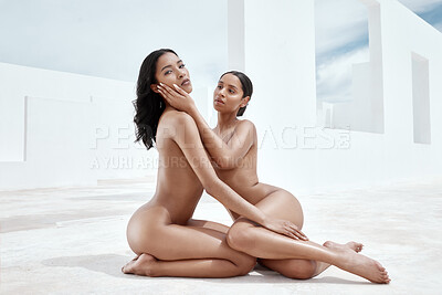 Full body of two mixed race women sitting outside side by side, posing nude on stairs and against white walls. Sexy hot hispanic models showing their naked bodies. Sensual nudists seductive and free