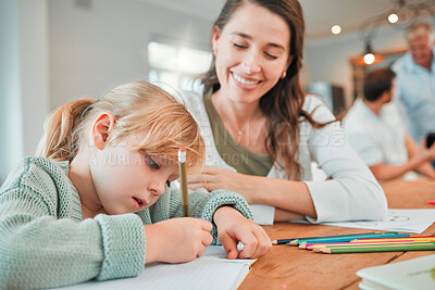 Buy stock photo Adorable little caucasian girl sitting at table and doing homework while her mother helps her. Beautiful smiling young woman bonding and teaching her daughter at home. Parent home schooling her child