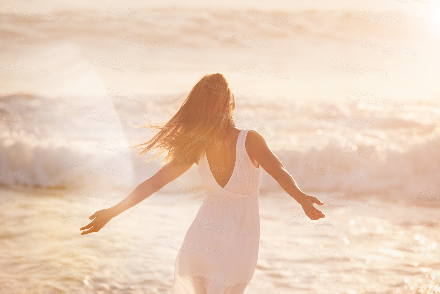 Buy stock photo a young woman enjoying her time at the beach. Carefree woman enjoying the sun on the beach. Back of a carefree content woman celebrating and enjoying the sunset on the beach