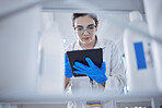 One beautiful young caucasian medical scientist wearing glasses and looking at a digital tablet in a laboratory. Healthcare pathologist discovering a cure in a clinic. Controlling disease with science