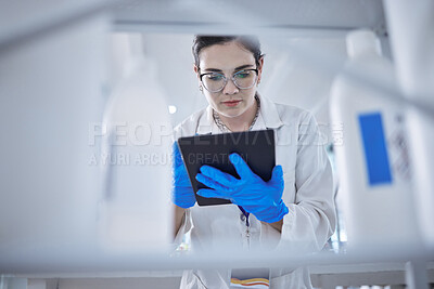 Buy stock photo One beautiful young caucasian medical scientist wearing glasses and looking at a digital tablet in a laboratory. Healthcare pathologist discovering a cure in a clinic. Controlling disease with science