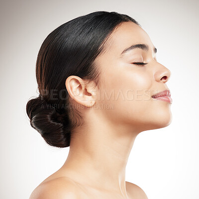 Buy stock photo Side of a young beautiful mixed race woman’s face smiling and posing against a grey studio background. Content hispanic female posing against a background